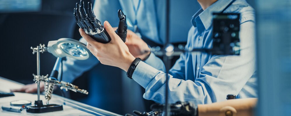Technological Prosthetic Robot Arm is Tested by Two Professional Development Engineers in a High Tech Research Laboratory with Modern Futuristic Equipment. Compare Data on a Personal Computer.
